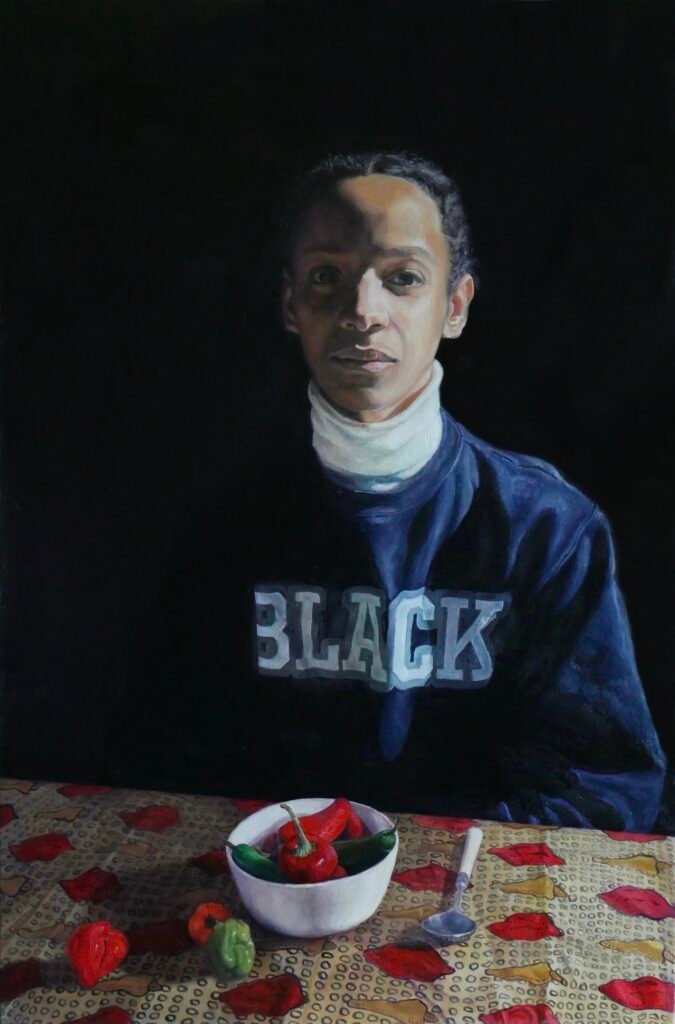 Black woman sitting in the dark in front of a bowl of chilli peppers